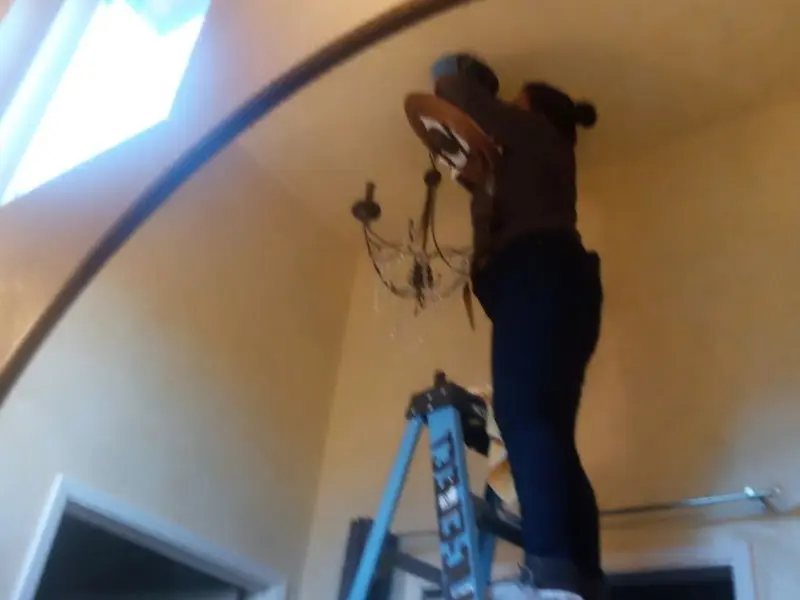 Electrician installing a chandelier in a Lincoln residence